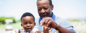 Older man playing chess with grandson