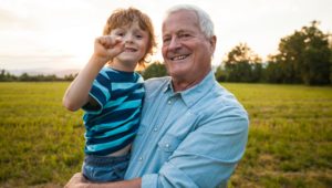 Older man holding grandson outside