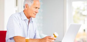 Older man looking at pill bottle.