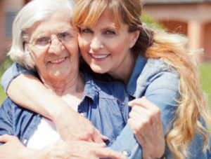 Daughter hugging aging mother that she cares for