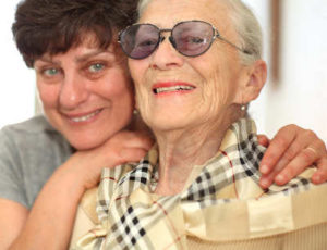 Middle aged daughter hugging aging mother.