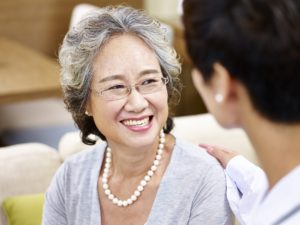 happy smiling senior woman talking and being comforted by another personr.