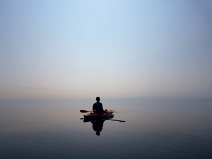 Man on Kayak in large lake represents isolation and loneliness for those caring for aging family members