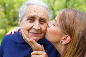 Daughter kissing mother with Alzheimer's diseas