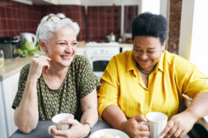 Two older women laughing over coffee.