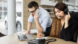 Two staff members on the phone with older adults, helping them fill out forms, and receive the care they need.