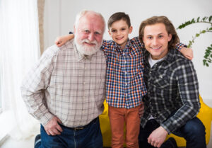 A family photo of an older man and his two grandkids. The older man is on the far left, his grandson elementary aged is in the middle, with his other grandson high school age on the far right.