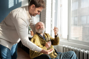 An older man taking medicine that is being given to him by his caregiver.
