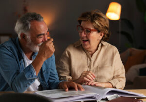 An women and her husband, joyfully reminiscing at family photos.