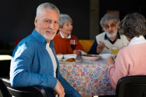 An older man enjoying dinner with his friends.