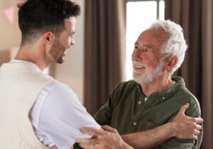 A son and his father hugging and smiling at each other.