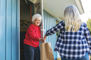 In Western Colorado Mature Adult Female Delivering Groceries to Senior Elderly Adult Female and Social Distancing Due to Infectious Virus Outbreak Pandemic Series (Shot with Canon 5DS 50.6mp photos professionally retouched - Lightroom / Photoshop - original size 5792 x 8688 downsampled as needed for clarity and select focus used for dramatic effect)